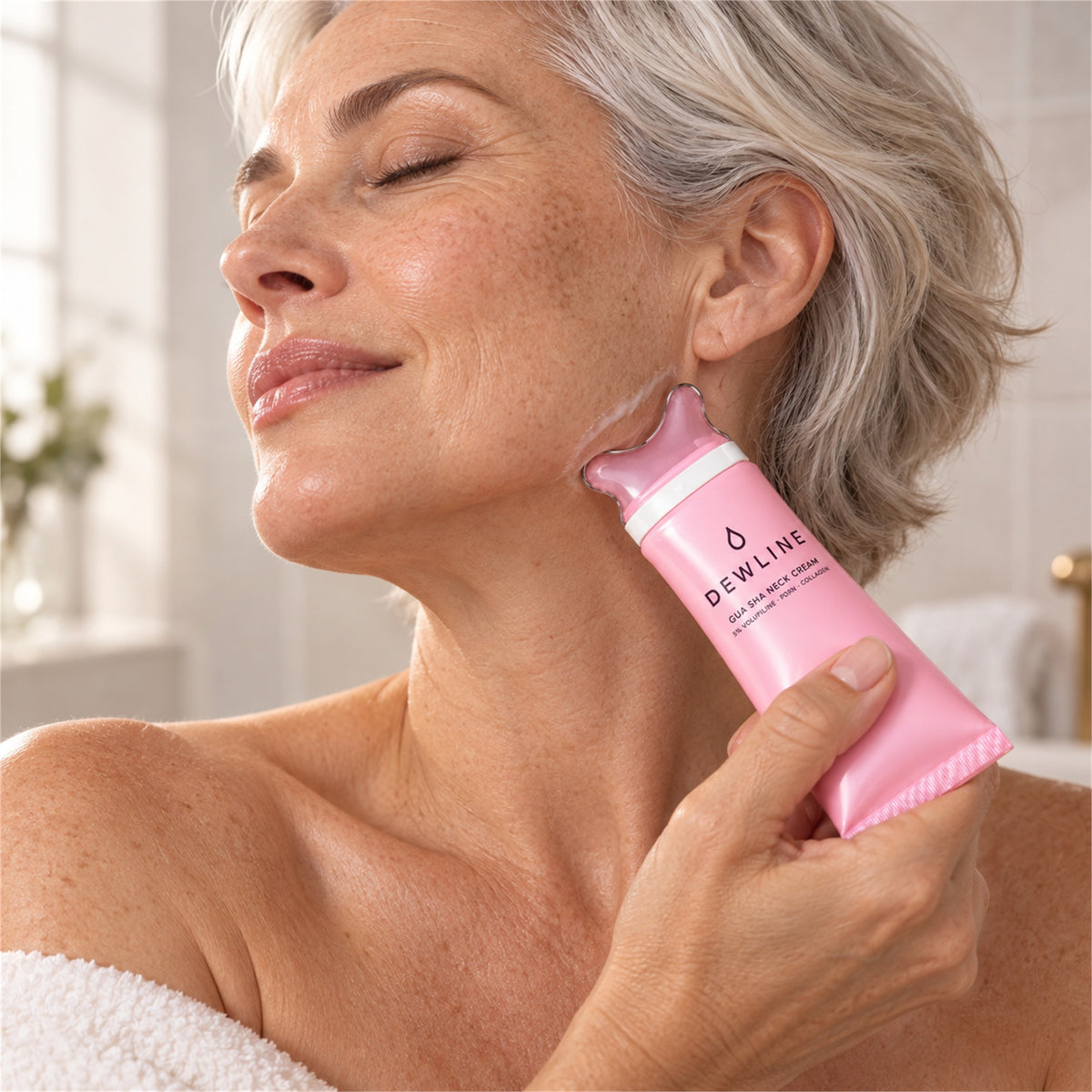 A woman gliding the Dewline gua sha cap along her jawline